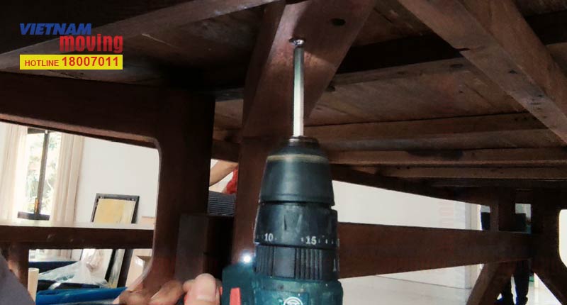 Dùng máy khoan tháo vít để tháo bàn ghế